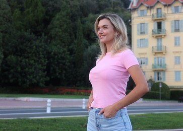 Photo of Happy young woman in casual clothes outdoors, space for text
