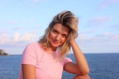 Photo of Portrait of happy young woman near sea on summer day