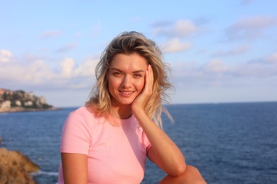 Photo of Portrait of happy young woman near sea on summer day