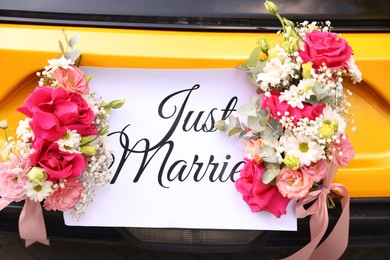 Photo of Wedding car. Cabriolet decorated with Just Married card and beautiful flowers outdoors, closeup