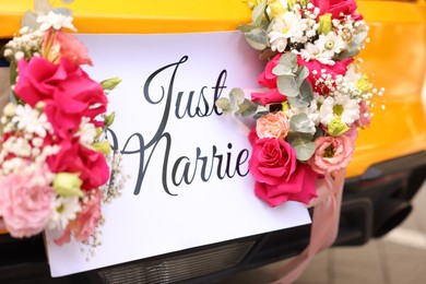 Photo of Wedding car. Cabriolet decorated with Just Married card and beautiful flowers outdoors, closeup