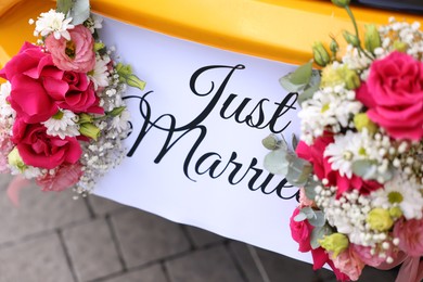 Photo of Wedding car. Cabriolet decorated with Just Married card and beautiful flowers outdoors, closeup