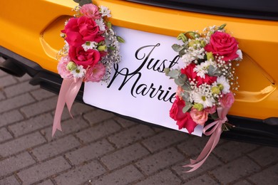 Photo of Wedding car. Cabriolet decorated with Just Married card and beautiful flowers outdoors, closeup