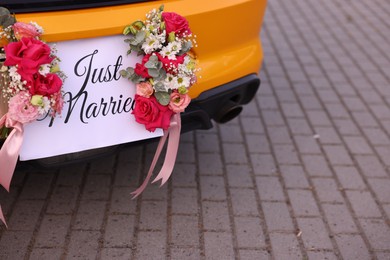 Photo of Wedding car. Cabriolet decorated with Just Married card and beautiful flowers outdoors, closeup