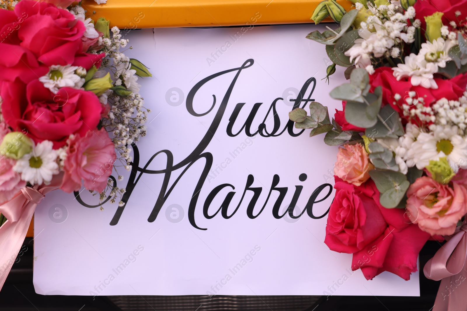 Photo of Wedding car. Cabriolet decorated with Just Married card and beautiful flowers outdoors, closeup