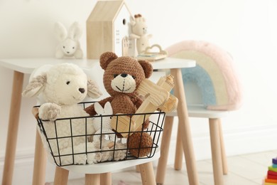 Photo of Different cute toys in metal basket on chair indoors