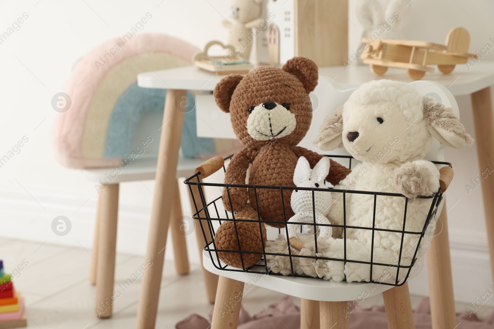 Photo of Different cute toys in metal basket on chair indoors