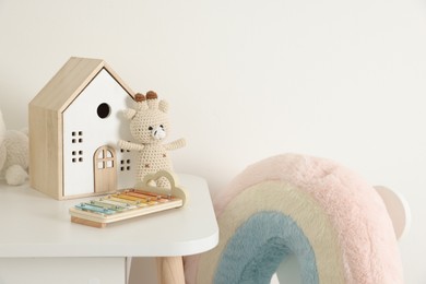 Photo of Different toys on table and chair near white wall