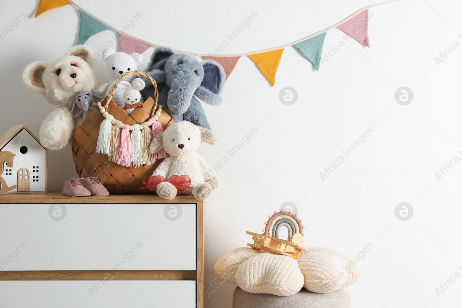 Photo of Different toys on chest of drawers near white wall indoors. Space for text