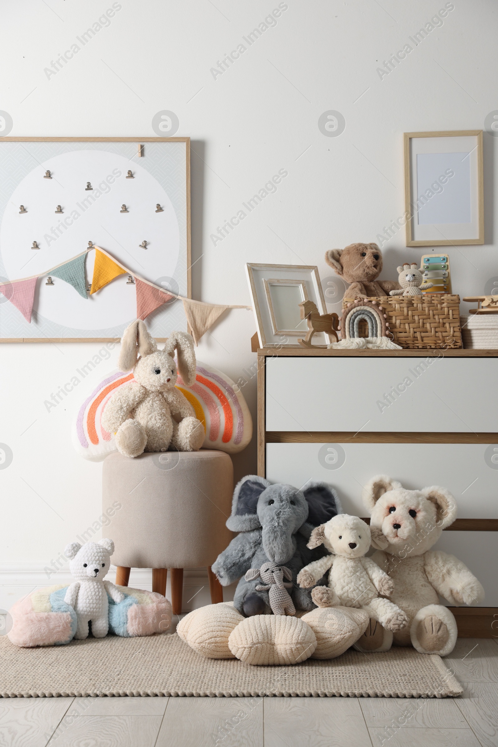 Photo of Different cute toys, furniture and garland in child's room