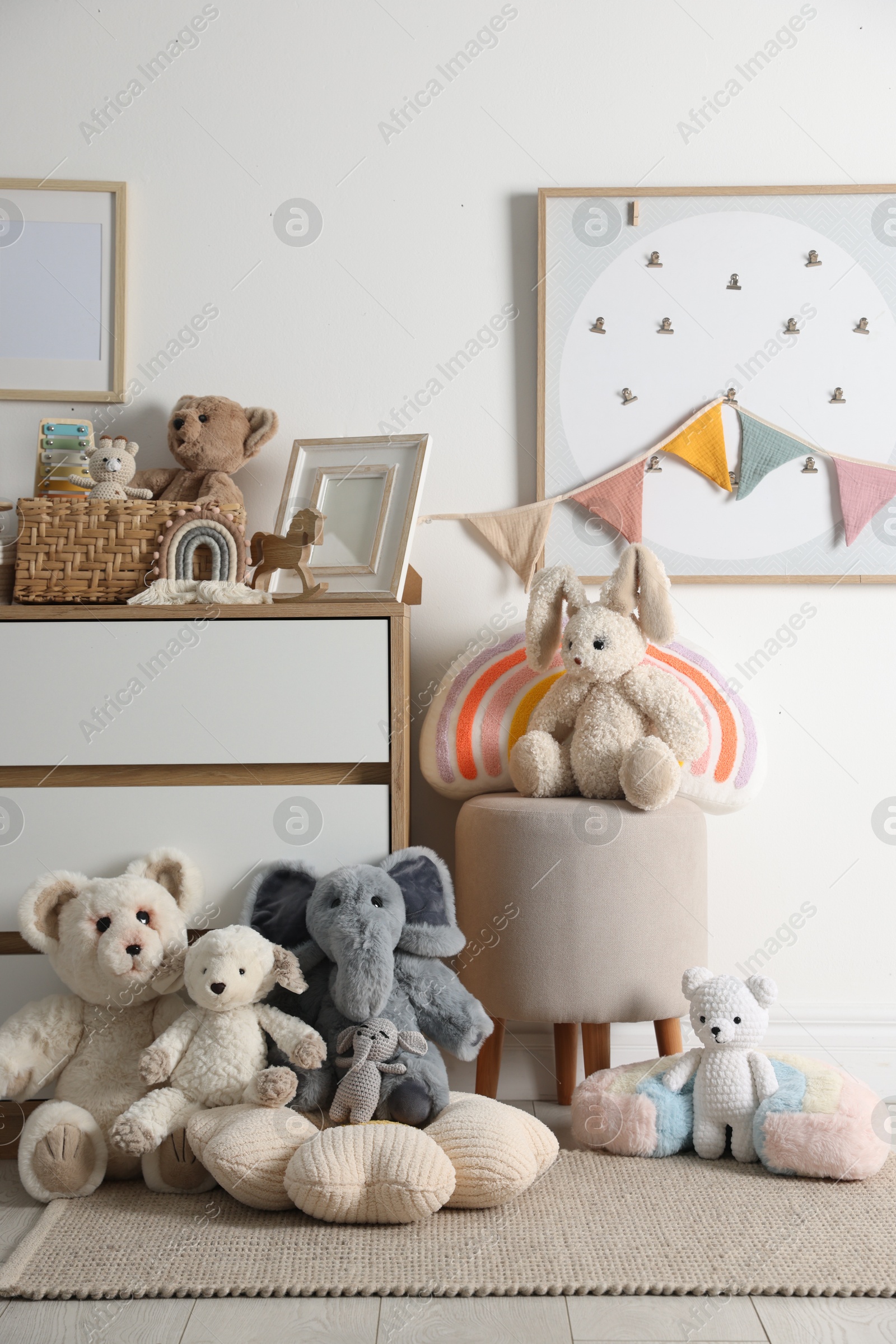 Photo of Different cute toys, furniture and garland in child's room
