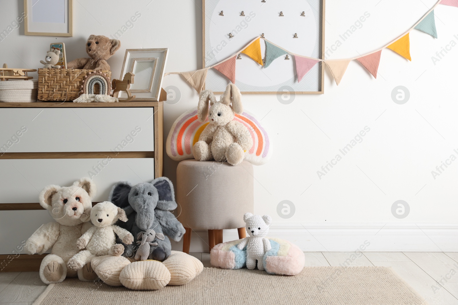 Photo of Different cute toys, furniture and garland in child's room. Space for text