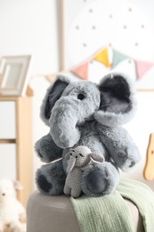 Photo of Cute soft toy elephants on pouf in child's room, closeup