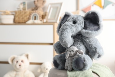 Photo of Cute soft toy elephants on pouf in child's room, closeup. Space for text