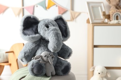 Photo of Cute soft toy elephants on pouf in child's room, closeup. Space for text