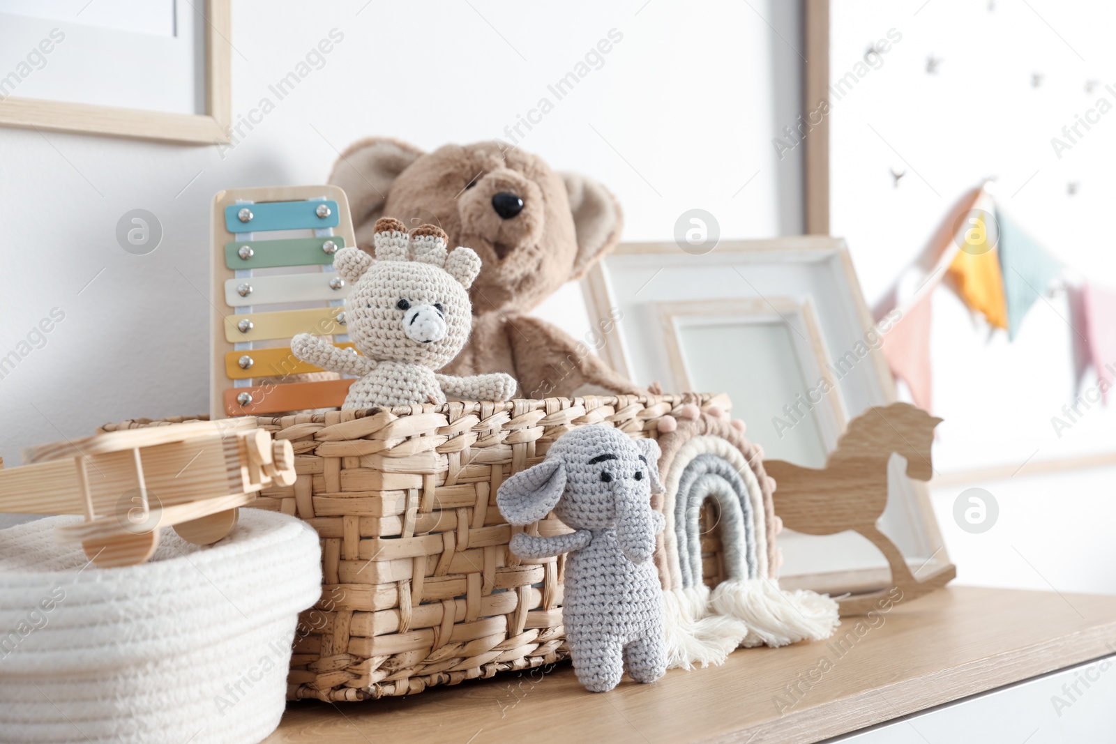 Photo of Different cute toys and decor on wooden table near white wall indoors