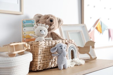 Photo of Different cute toys and decor on wooden table near white wall indoors