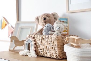 Photo of Different cute toys and decor on wooden table near white wall indoors