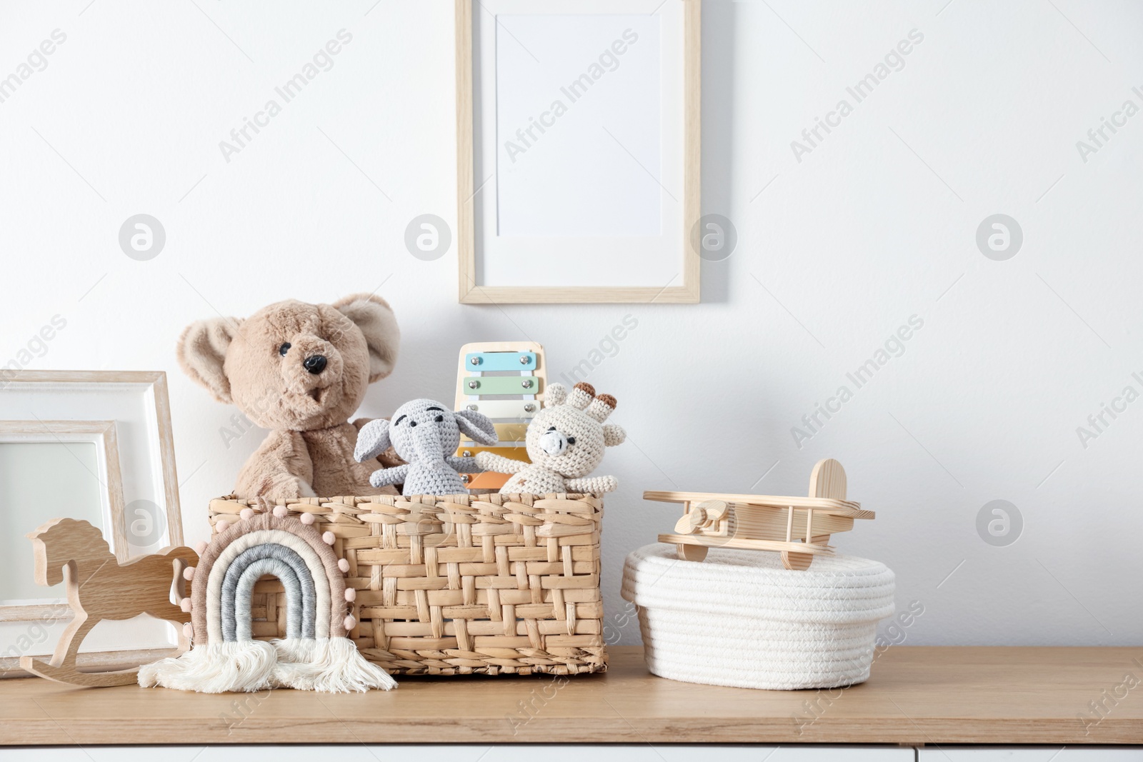 Photo of Different cute toys and decor on wooden table near white wall
