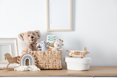Photo of Different cute toys and decor on wooden table near white wall