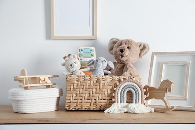 Photo of Different cute toys and decor on wooden table near white wall