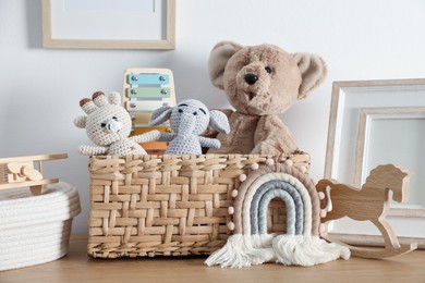 Photo of Different cute toys and decor on wooden table near white wall
