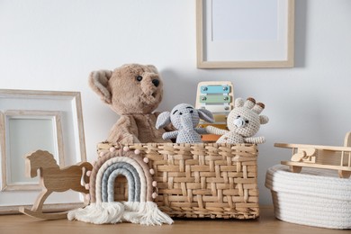 Photo of Different cute toys and decor on wooden table near white wall