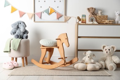 Photo of Different cute toys, furniture and garland in child's room