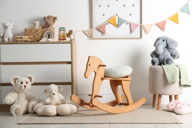 Photo of Different cute toys, furniture and garland in child's room