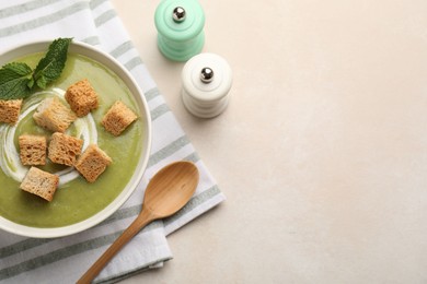 Photo of Salt and pepper mills near bowl of delicious cream soup with croutons and mint on light table, flat lay. Space for text