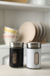 Photo of Salt and pepper shakers on light wooden table in kitchen, closeup. Space for text