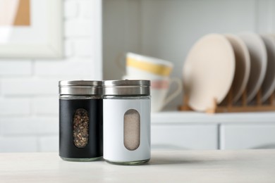 Photo of Salt and pepper shakers on light wooden table in kitchen, closeup. Space for text