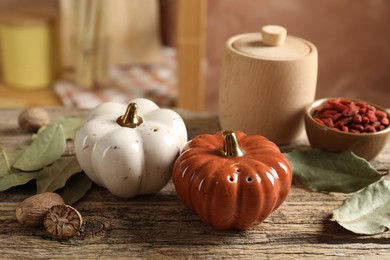 Photo of Salt, pepper shakers in shape of pumpkins and spices on wooden table against blurred brown background, closeup