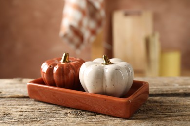 Photo of Salt and pepper shakers in shape of pumpkins on wooden table in kitchen, closeup