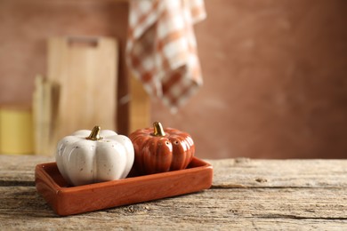 Photo of Salt and pepper shakers in shape of pumpkins on wooden table in kitchen, closeup. Space for text