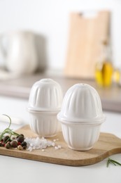 Photo of Salt, pepper shakers and spices on white table in kitchen