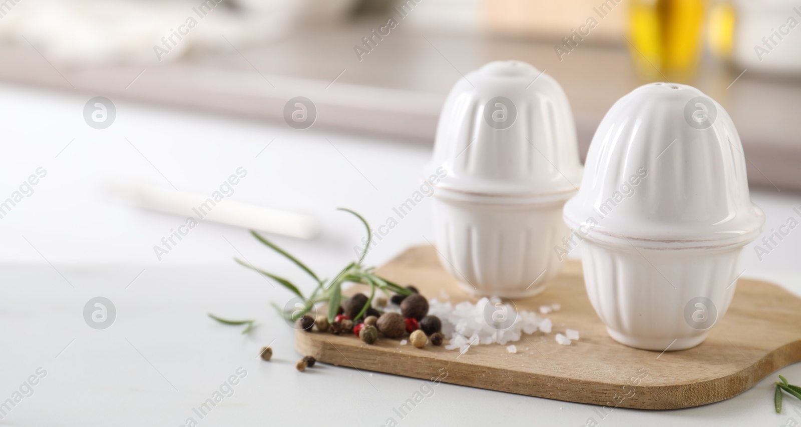 Photo of Salt, pepper shakers and spices on white table indoors, closeup. Space for text