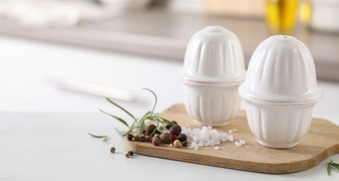 Photo of Salt, pepper shakers and spices on white table indoors, closeup. Space for text