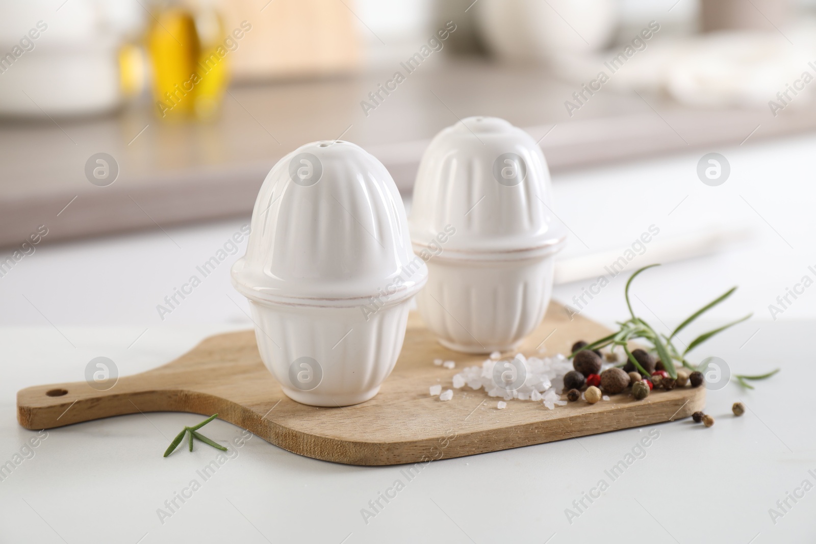 Photo of Salt, pepper shakers and spices on white table indoors, closeup