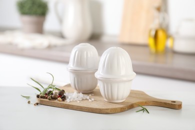 Photo of Salt, pepper shakers and spices on white table indoors, closeup