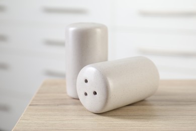 Photo of Salt and pepper shakers on wooden table indoors, closeup