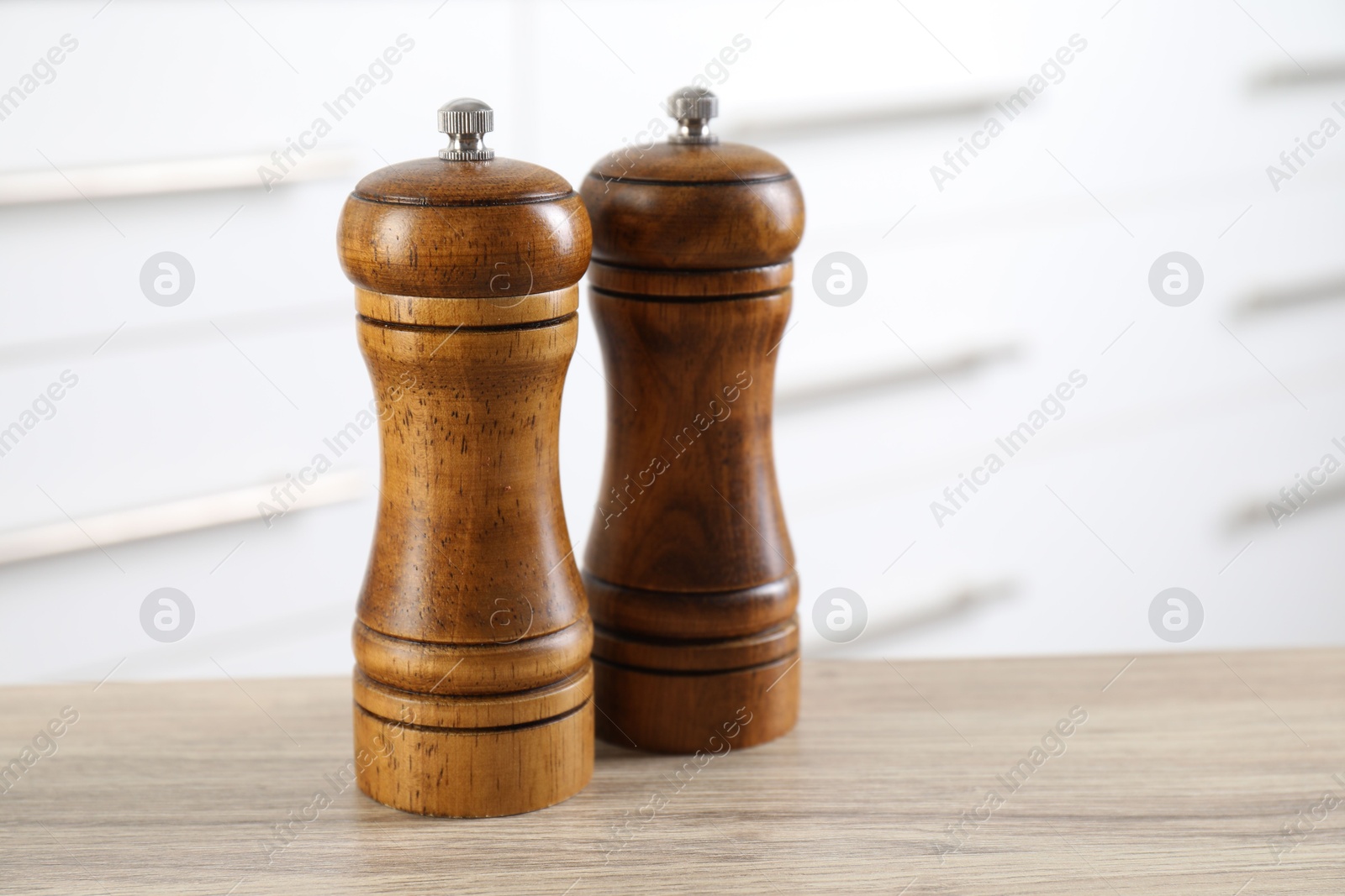 Photo of Salt and pepper mills on wooden table indoors, closeup. Space for text