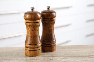 Photo of Salt and pepper mills on wooden table indoors, closeup. Space for text