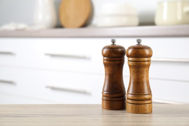 Photo of Salt and pepper mills on wooden table indoors, closeup. Space for text