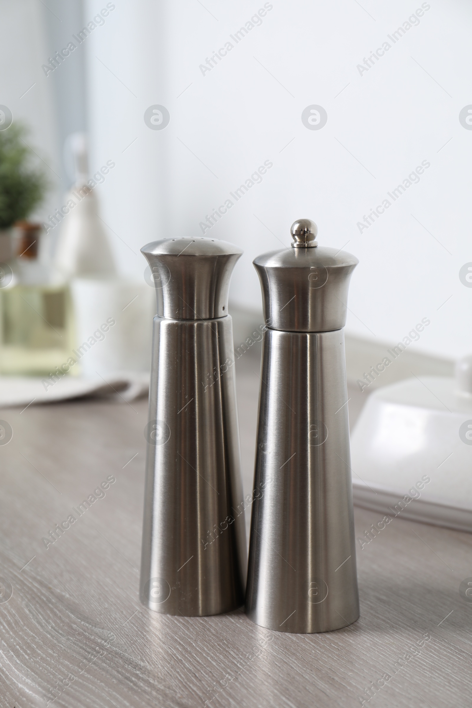 Photo of Metal salt and pepper mills on grey wooden counter indoors
