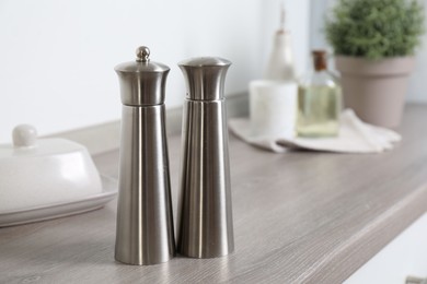 Photo of Metal salt and pepper mills on grey wooden counter indoors, closeup. Space for text
