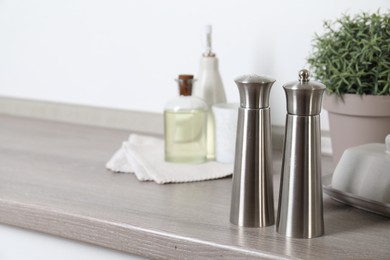Photo of Metal salt and pepper mills on grey wooden counter indoors, closeup. Space for text