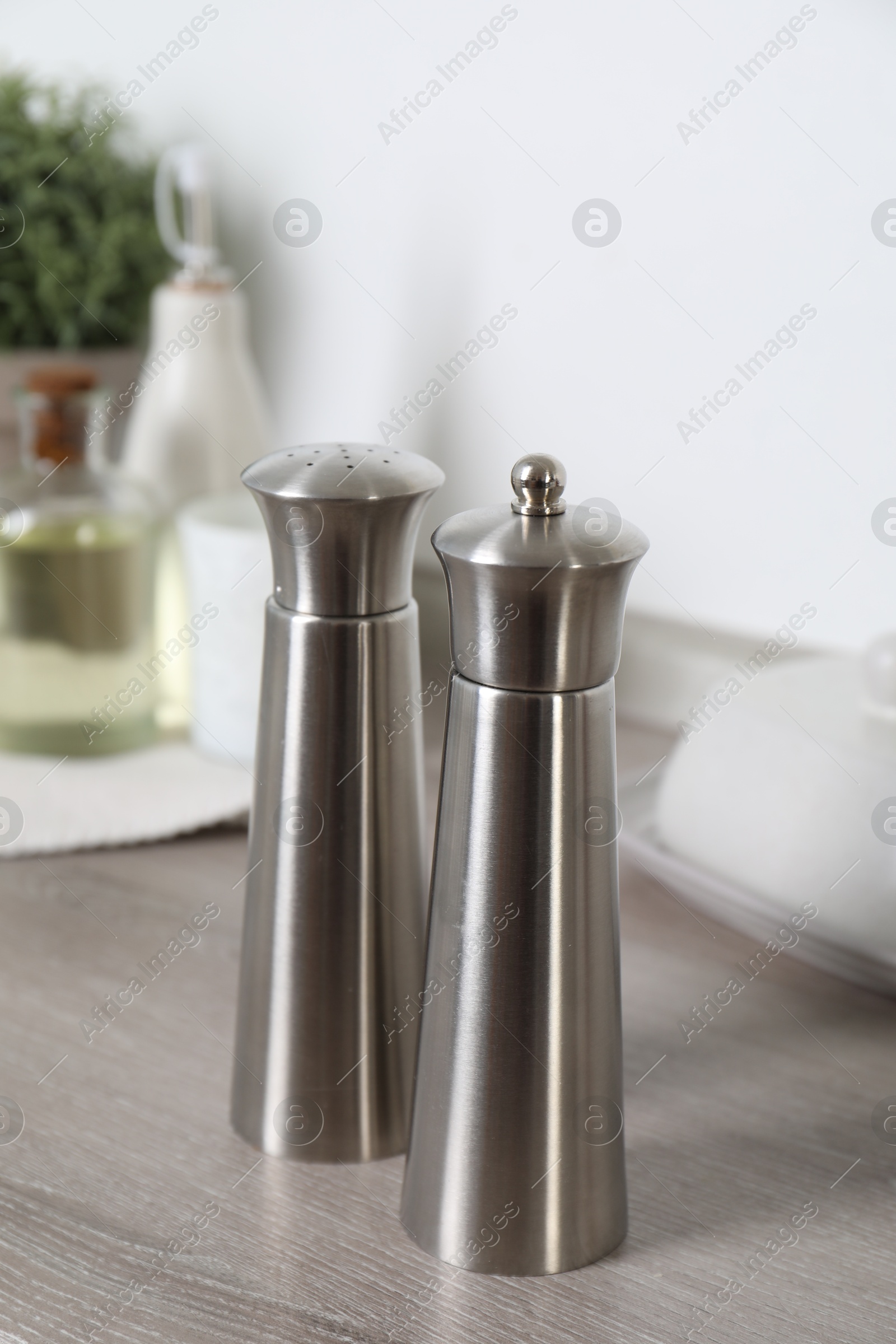 Photo of Metal salt and pepper mills on grey wooden counter indoors, closeup