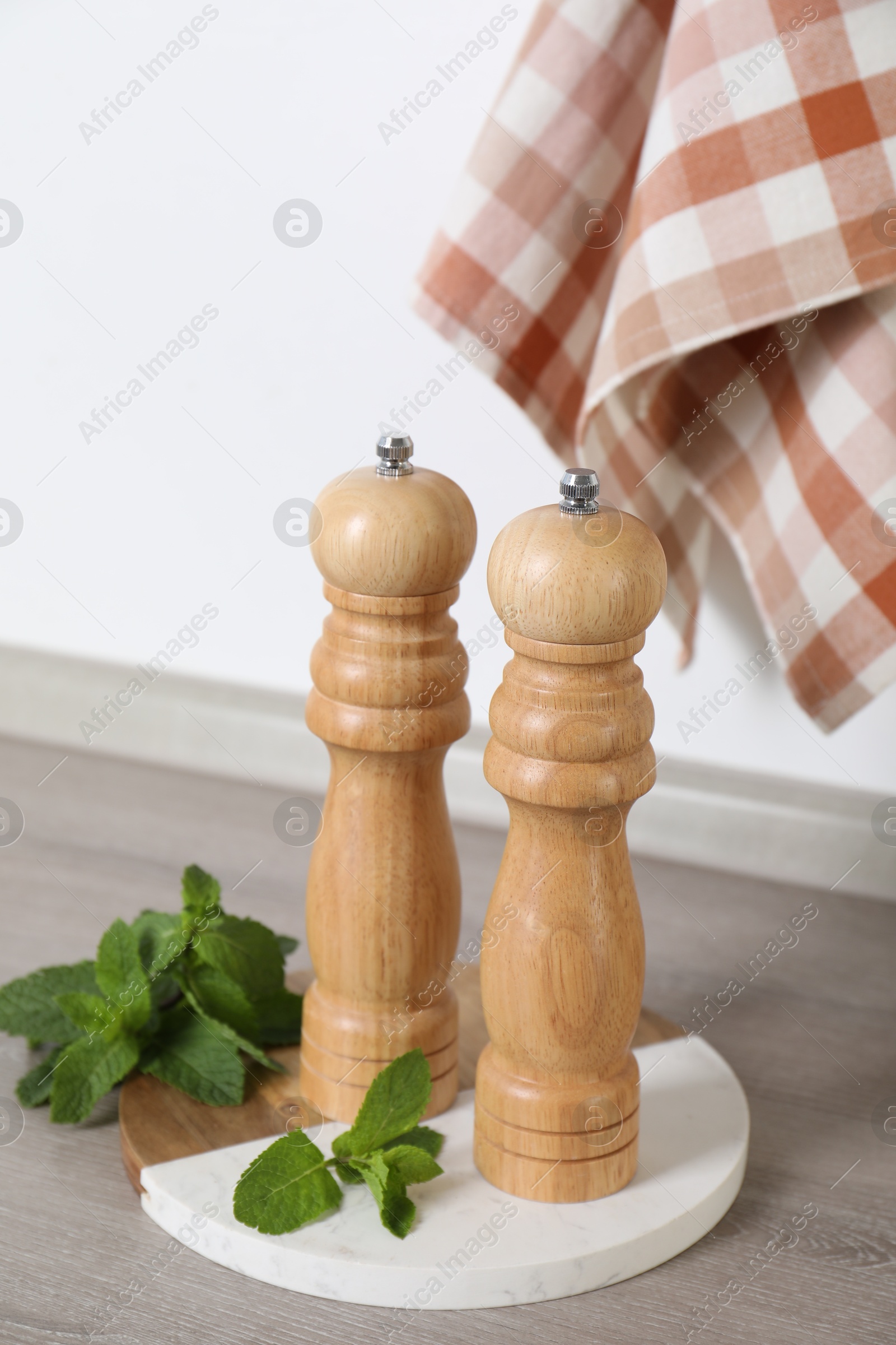 Salt, pepper mills and mint on grey wooden counter near white wall, closeup Photo of Salt, pepper mills and mint on grey wooden counter near white wall, closeup