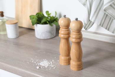 Photo of Salt and pepper mills on grey wooden counter indoors, closeup